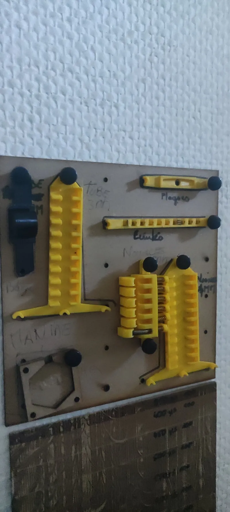 Plusieurs gabarits jaunes conçus par µsini pour les bijoux Manine, rangés sur un panneau